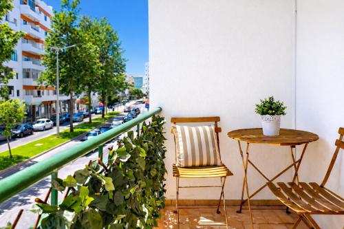a table and chairs on a balcony with a street at Avenue Apartment - Family-friendly T2 - Estacionamento Privado in Quarteira