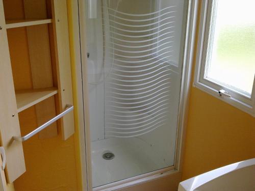 a glass shower in a bathroom with a window at Mobilhome 3 slaapkamers Ardoercamping Landingsweg 1 in Baarland