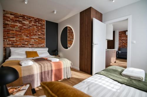 a bedroom with two beds and a brick wall at Calma - apartamenty z ogrodem blisko Energylandii in Zator