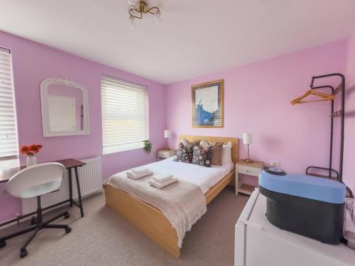 a bedroom with purple walls and a bed and a desk at Camden Rooms in London