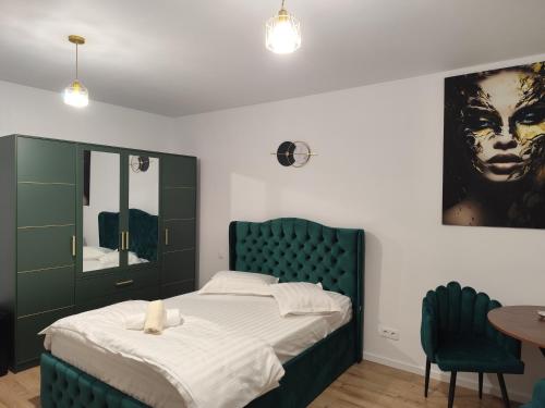 a bedroom with a bed with a green headboard and a table at Vivien Residence 2 in Baia Mare