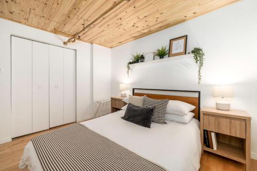 a bedroom with a bed with white walls and a wooden ceiling at Lion's Den // Spacious 1500 sqft (2 WC) - Downtown in Quebec City