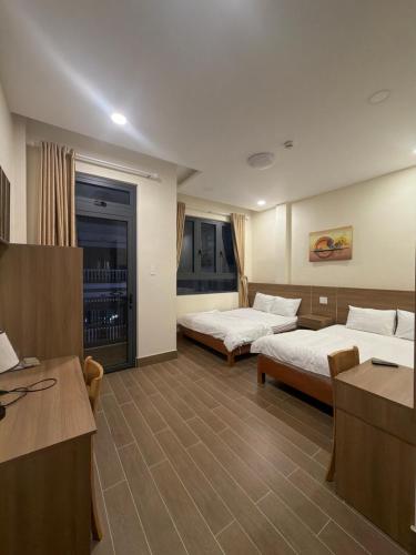 a hotel room with two beds and a desk at Rosie Hotel in Da Thien