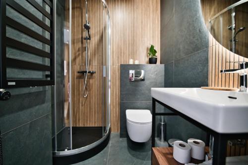 a bathroom with a sink and a shower and a toilet at Calma - apartamenty z ogrodem blisko Energylandii in Zator