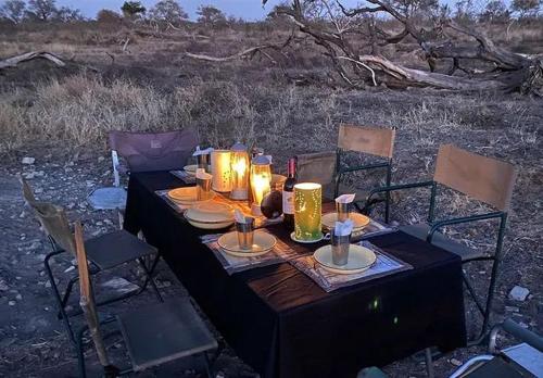 a black table with candles and plates and chairs at Zambezi Dream Cruiser in Victoria Falls