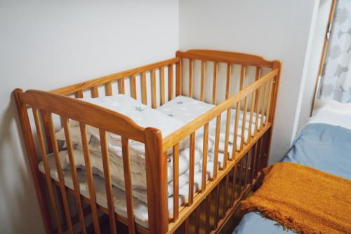 a wooden crib in a room with a bed at TENT OKAYAMA - 3 Bedrooms, 100m2 Private Home for Max 8 people, Ideal for Families and Groups in Hokancho