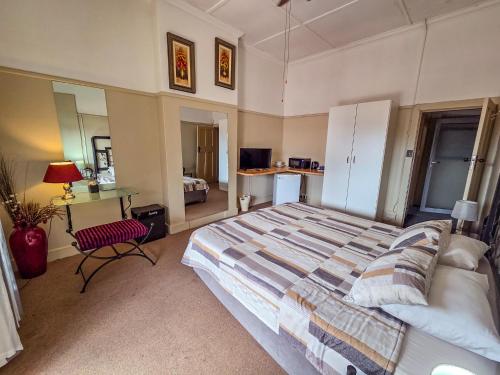 a bedroom with a large bed and a desk at Die Suidwester Gastehuis in Parys