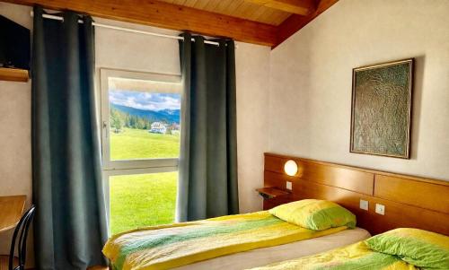 a bedroom with a bed and a large window at Hôtel La Croisée Neuchâtel in Malvilliers
