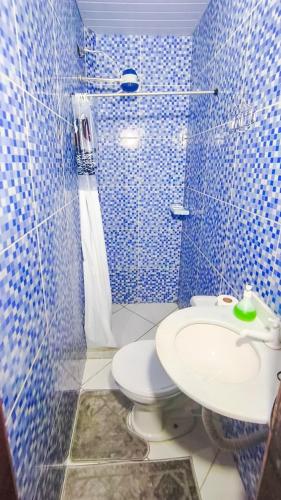 a blue tiled bathroom with a toilet and a sink at Hostel Sundays in Angra dos Reis