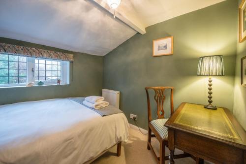 a bedroom with a bed and a table with a lamp at Hollyhocks, Tunstall in Tunstall