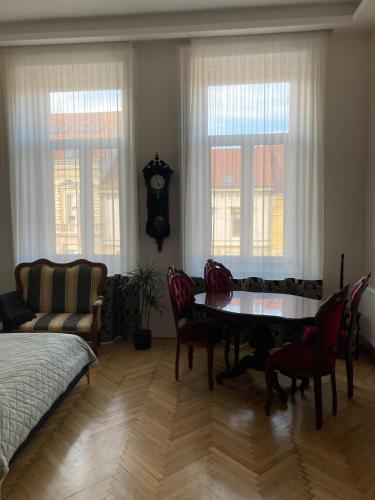 a living room with a table and chairs and a clock at LILI Deluxe Apartman in Tapolca