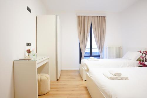 a white bedroom with two beds and a window at Sunshine HOTEL in Mestre