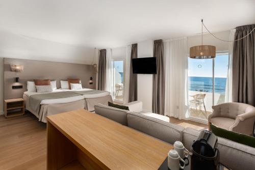 a hotel room with two beds and a couch at FERGUS Style Palma Beach - Adults Only in Can Pastilla