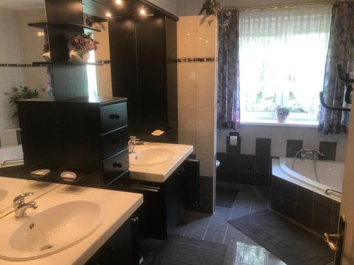 a bathroom with two sinks and a bath tub and a window at Ferienhaus Marhardt in Oslip
