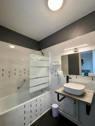 a white bathroom with a sink and a tub at Logis Hôtel de la Bruyere in Pouzauges