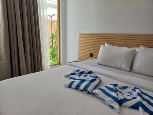 a bed with two towels on it with a window at Dhigurah Holidays in Dhigurah