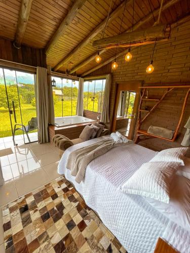 a bedroom with a large bed and a large window at Chalés Aconchego dos Canyons in Praia Grande