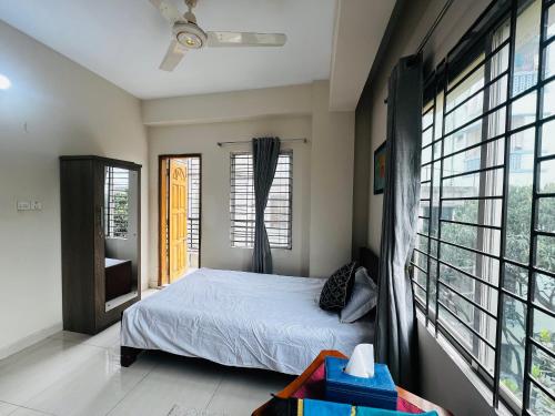 a bedroom with a bed and large windows at Gulshan Guest House in Dhaka