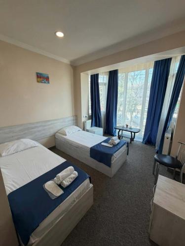 zwei Betten in einem Hotelzimmer mit blauen Vorhängen in der Unterkunft Platformatbilisi in Tbilisi City