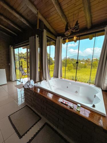a large bath tub in a room with windows at Chalés Aconchego dos Canyons in Praia Grande