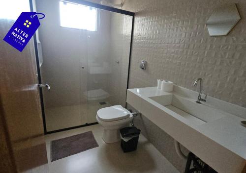 a bathroom with a shower and a toilet and a sink at Casa Coqueiro 02 in Primavera do Leste