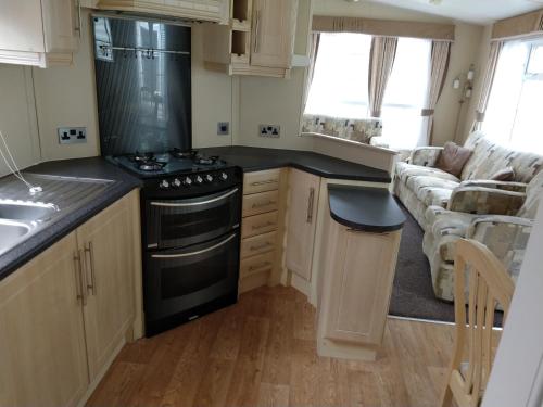 a kitchen with a stove and a living room at The Willows at Kingsmead Camping in West Buckland