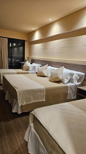 a group of three beds in a hotel room at Andes Xtreme Hotel Boutique in Tinogasta