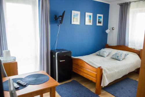 a small bedroom with a bed and a blue wall at Noclegi U Asi in Polańczyk