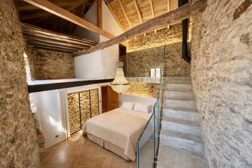 a bedroom with a bed and a staircase in a stone wall at Villa San Martino in San-Martino-di-Lota