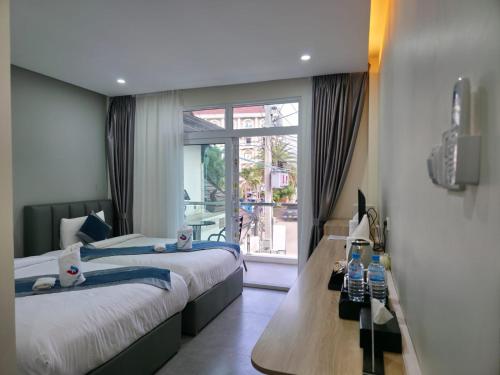 a bedroom with two beds and a large window at Tulip Elegant Riverside Hotel in Vang Vieng