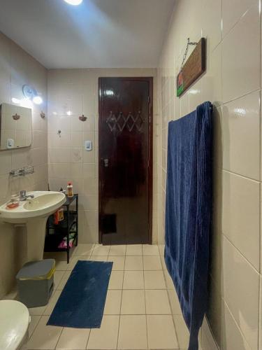 a bathroom with a sink and a shower with a blue towel at Casa com 2 suítes com ar in Cabo Frio
