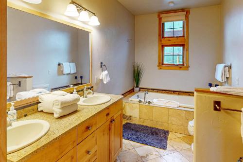 a bathroom with two sinks and a tub and a large mirror at Urban Mountain Getaway & Alpenglow Chalet in Steamboat Springs