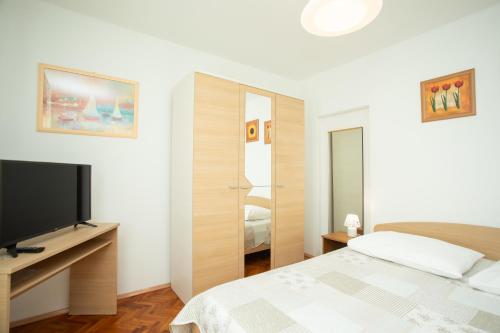 a bedroom with a bed and a flat screen tv at Apartmani Zlata in Rabac