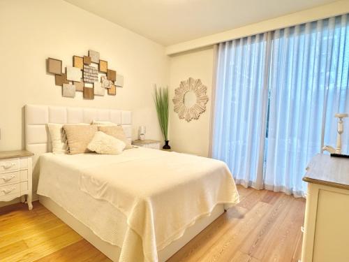 a white bedroom with a bed and a large window at DLux Terrace Cond Bayline Pool & SPA in Armação de Pêra