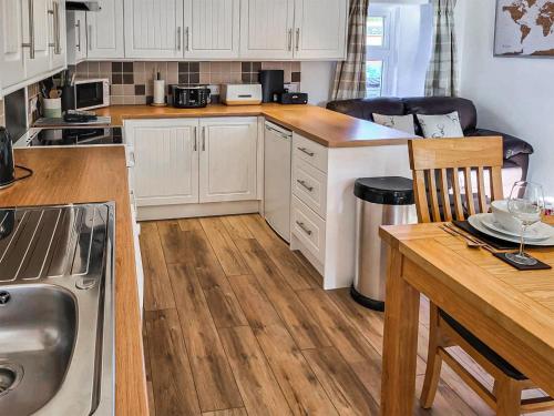 a kitchen with white cabinets and a wooden table at Jessamine Cottage in Blairgowrie