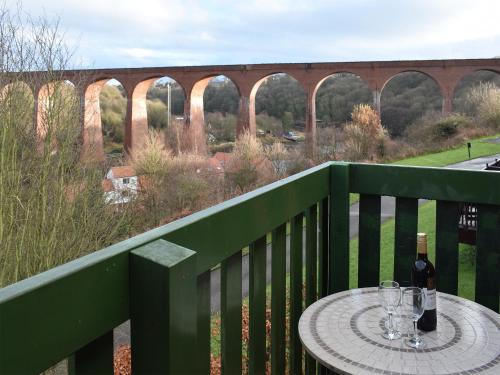 a table with wine glasses on a balcony with a bridge at Capstan Cottage in Whitby