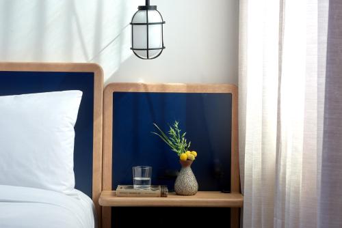 a bed with a nightstand with a vase of fruit on it at Emery Hotel, Autograph Collection in Minneapolis