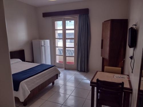 a bedroom with a bed and a table and a window at Hotel Plaza Olido in São Paulo