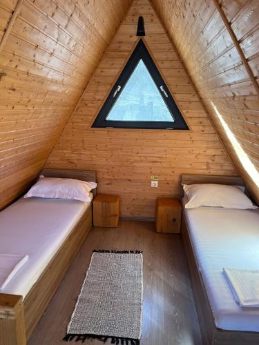 two beds in a wooden room with a window at La TRIUNGHIURI in Târgu Ocna