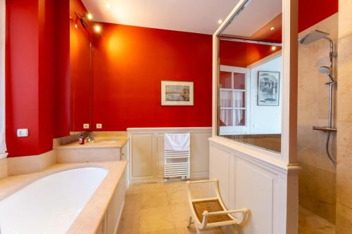 a bathroom with a tub and a red wall at Villa Blue Riviera & Le Joyau de la baie de Cannes in Cannes