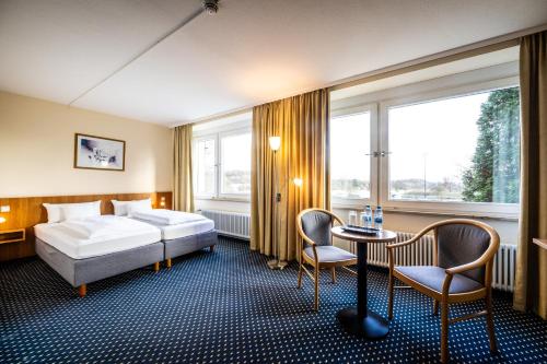 a hotel room with a bed and a table and chairs at Raststättenhotel Tecklenburger Land West in Tecklenburg