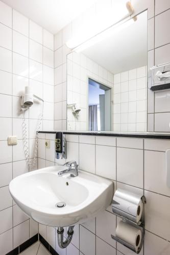 a white bathroom with a sink and a mirror at Raststättenhotel Tecklenburger Land West in Tecklenburg