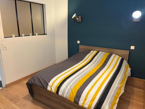 a bedroom with a bed with a colorful striped blanket at Agréable maison avec SPA in Crécy-en-Ponthieu