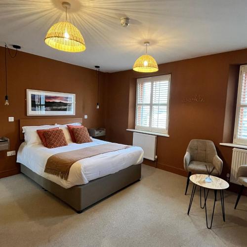 a bedroom with a large bed and two windows at Hues - Castle Cary in Castle Cary