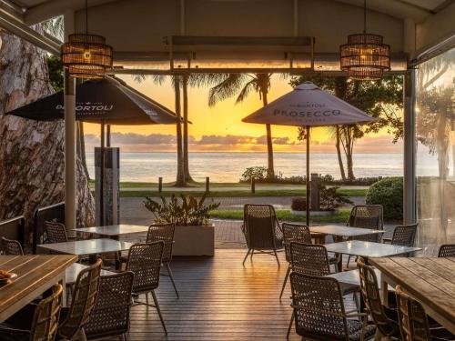 a restaurant with tables and chairs and a view of the ocean at Peppers Beach Club & Spa in Palm Cove