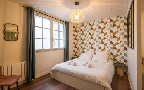 a bedroom with a white bed with a geometric wall at Le Parvis in Rodez