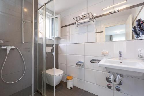 a bathroom with a shower and a toilet and a sink at Hotel Kernhof Self Check-In in Zurich