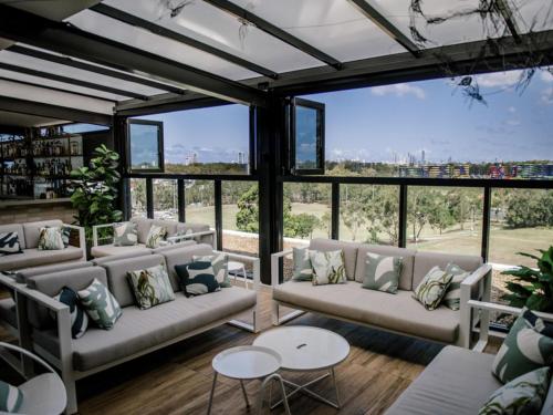 a living room with couches and tables and windows at Mantra at Sharks in Gold Coast