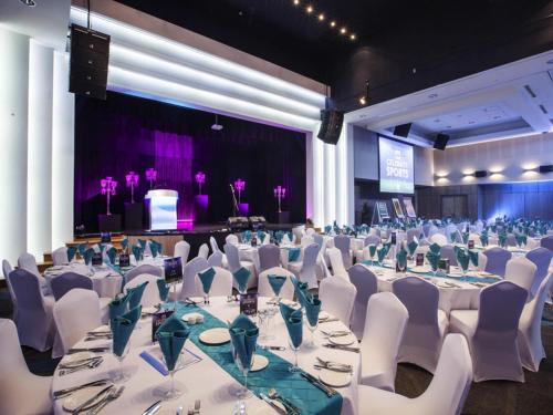 a large banquet hall with white tables and white chairs at Mantra at Sharks in Gold Coast