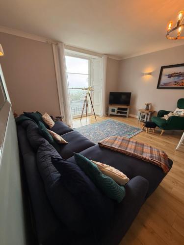 a living room with a black couch with pillows at Newton Croft Tenby overlooking North Beach in Tenby